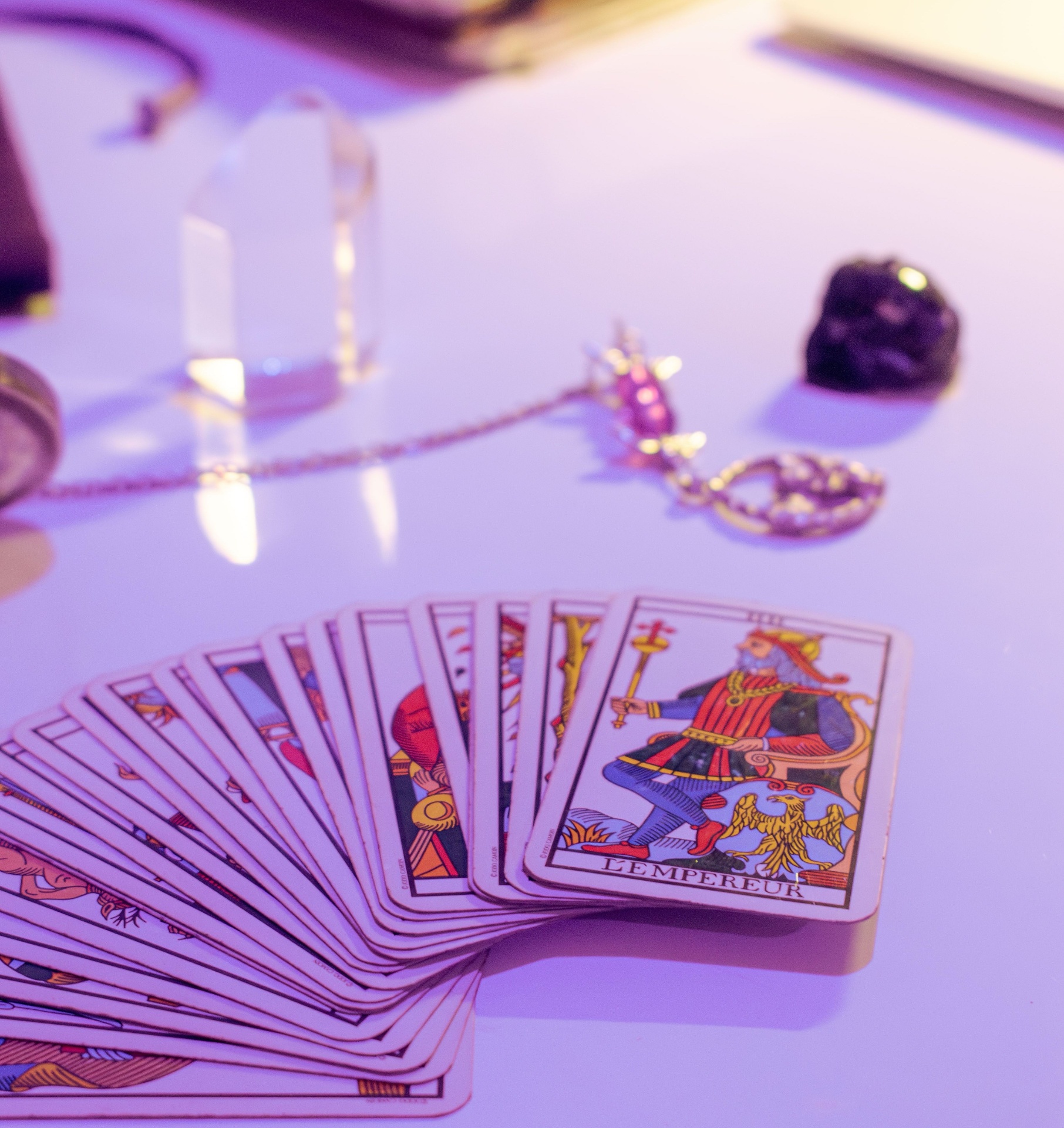 Tarot cards, crystals and pendulum on a softly lit table